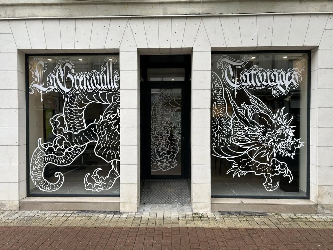 La vitrine de La Grenouille Tattoo : deux grandes baies ornées de dragons japonais peints en blanc
